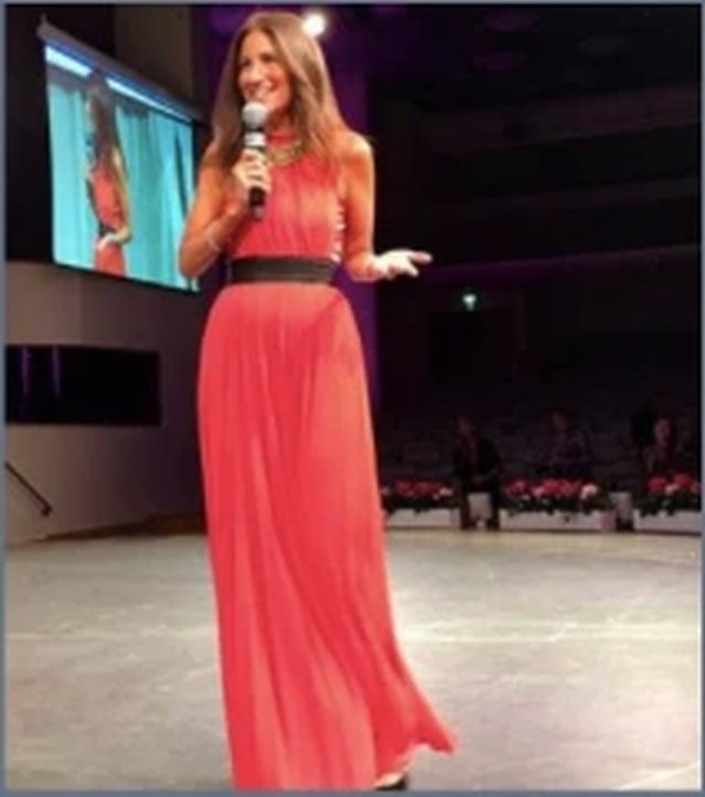 Korie Minkus speaking on stage in Sweden