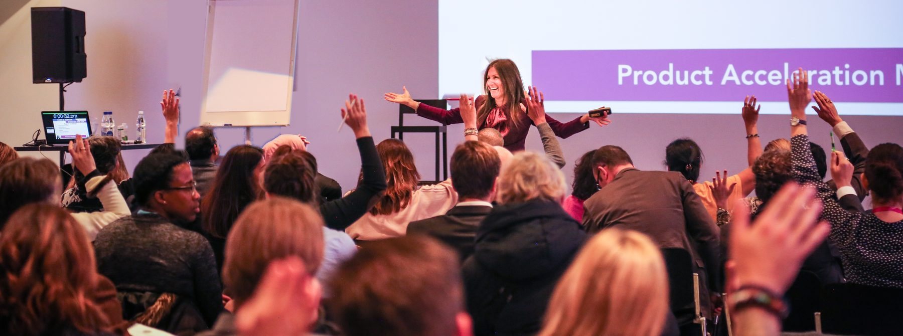 Korie Minkus training a full room of founders, hands raised across the audience