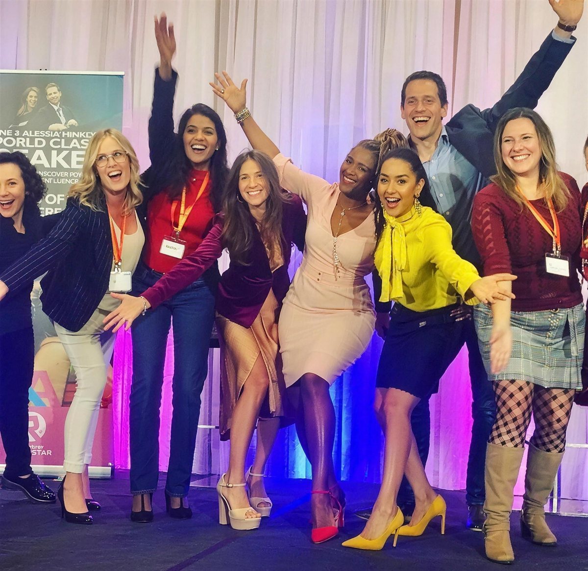 Korie Minkus on stage with arms raised, celebrating with the RYP team